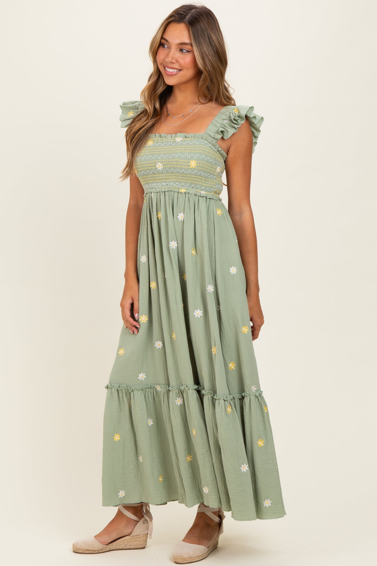 woman wearing a green maxi dress with ruffled sleeves and floral embroidery details