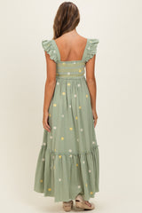 woman wearing a green floral embroidered maxi dress with ruffled straps and a smocked bodice, seen from the back