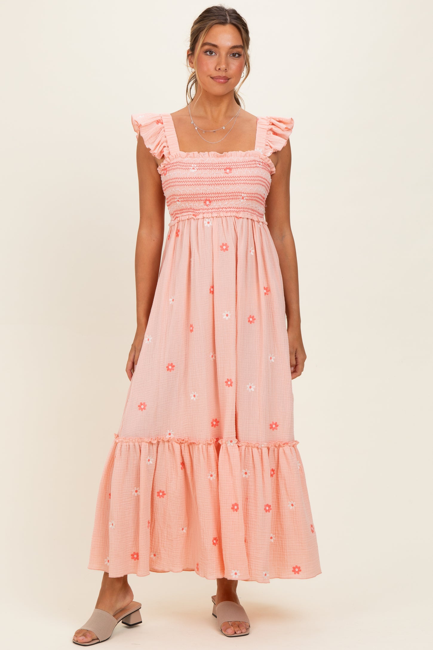 woman wearing a peach maxi dress with floral embroidery and ruffle straps