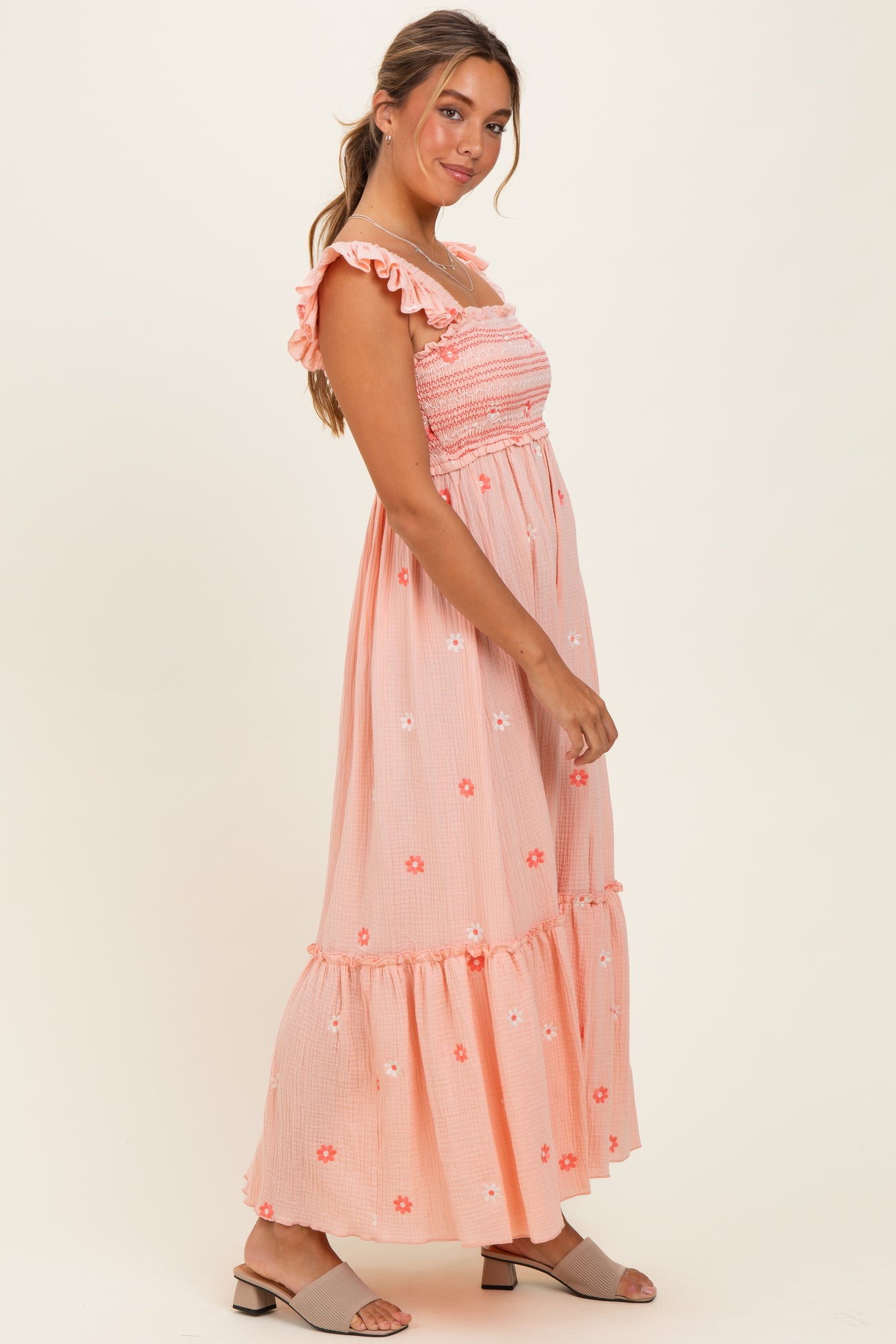 woman wearing a pink floral maxi dress with ruffled straps and a tiered hem