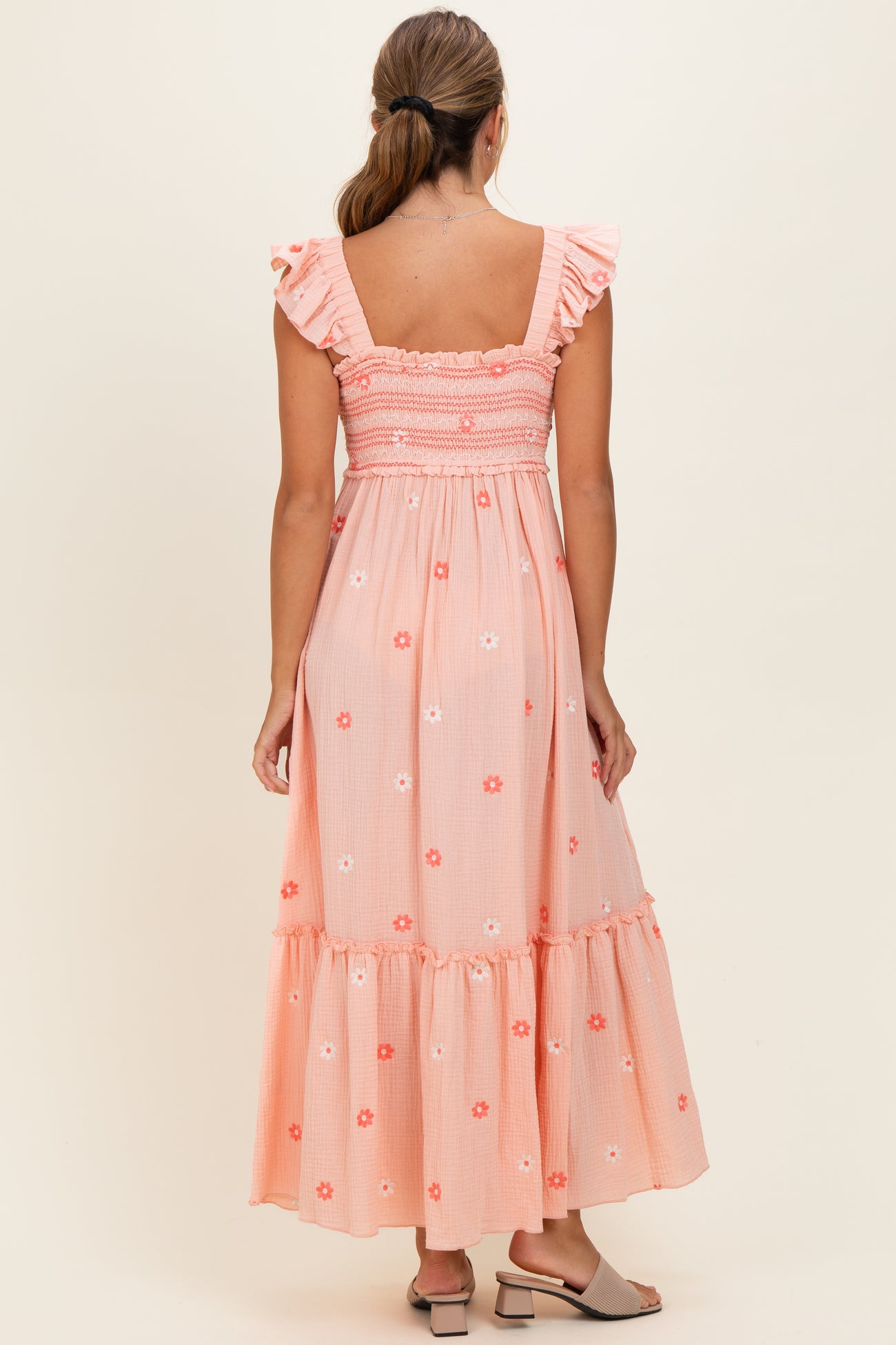 woman wearing a pink floral maxi dress with ruffle straps and tiered hem, seen from the back