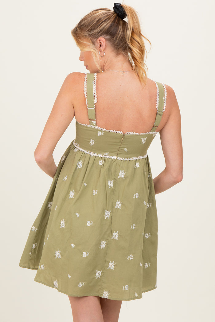 woman wearing a green embroidered maternity dress with adjustable straps and a flowy silhouette, showing her back