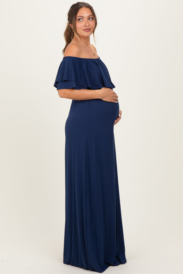 woman wearing a navy blue off-the-shoulder maternity dress, cradling her baby bump