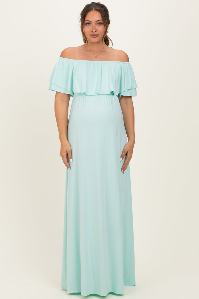 woman wearing a mint green off-the-shoulder maternity maxi dress with ruffle details and a visible baby bump