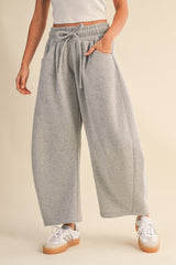 woman wearing gray wide-leg sweatpants with an elastic waistband and side pockets, paired with white sneakers