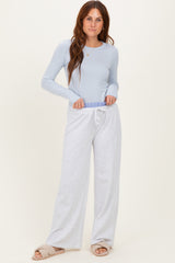 woman wearing a light blue long sleeve top and grey wide-leg sweatpants with an adjustable waistband