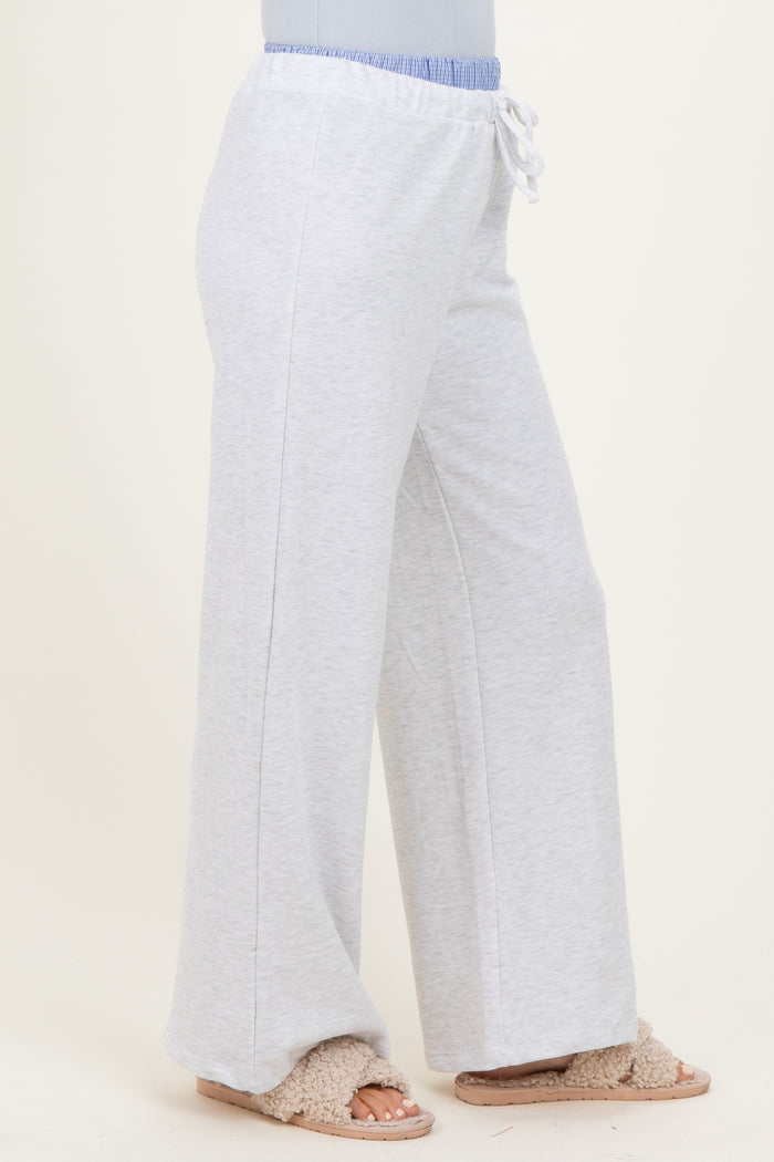 woman wearing light gray wide-leg sweatpants with an elastic waistband and drawstring detail, paired with cozy slippers