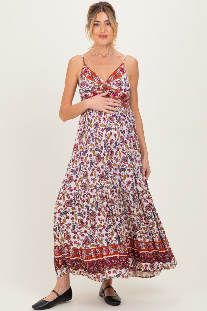 woman wearing a floral maxi maternity dress with adjustable straps and a twist front, featuring a visible baby bump