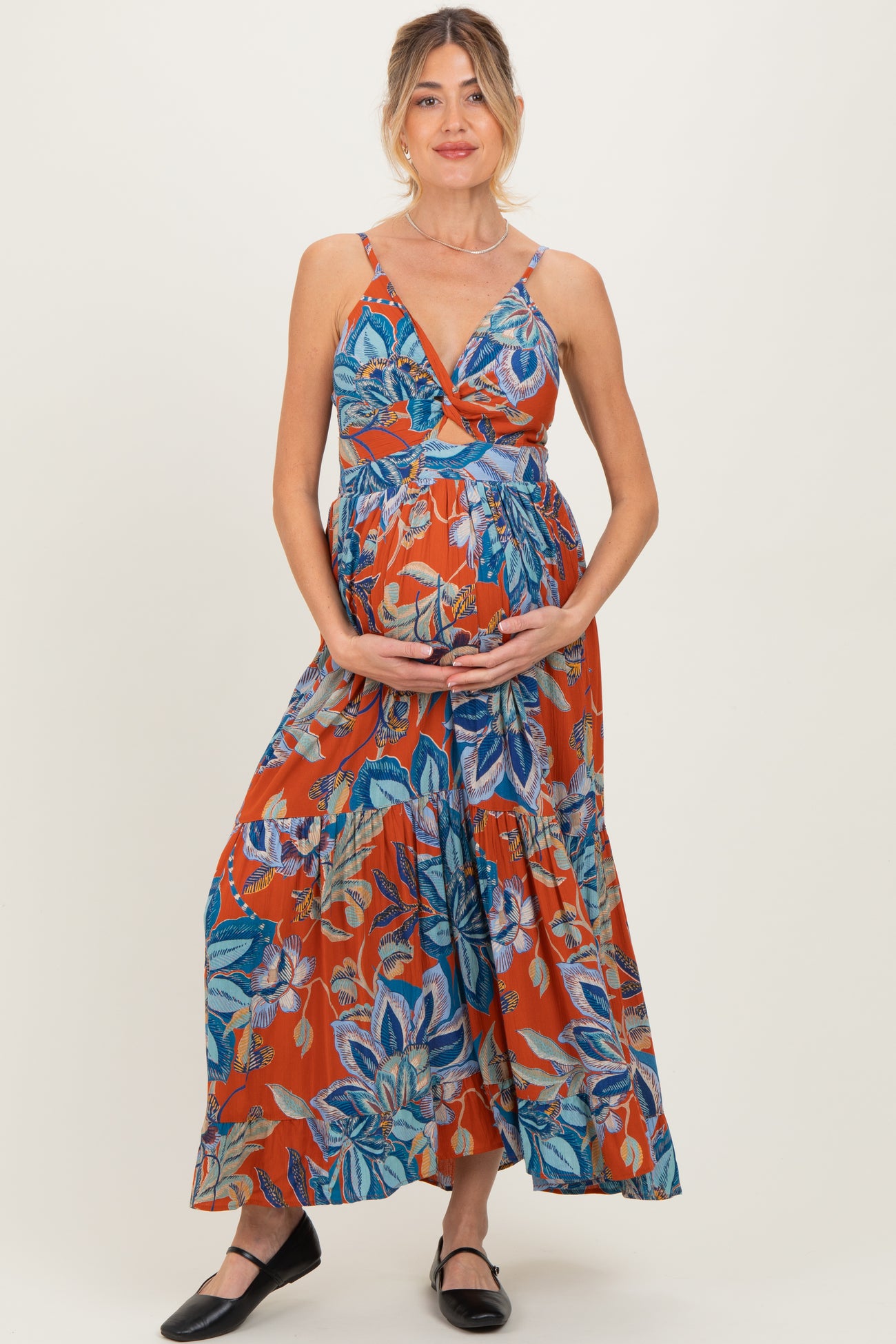 woman wearing a colorful floral maternity maxi dress and holding her baby bump