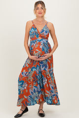 woman wearing a colorful floral maternity maxi dress and holding her baby bump