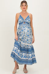 woman wearing a blue floral maternity maxi dress with a tie front detail and a flowing skirt, showcasing her baby bump