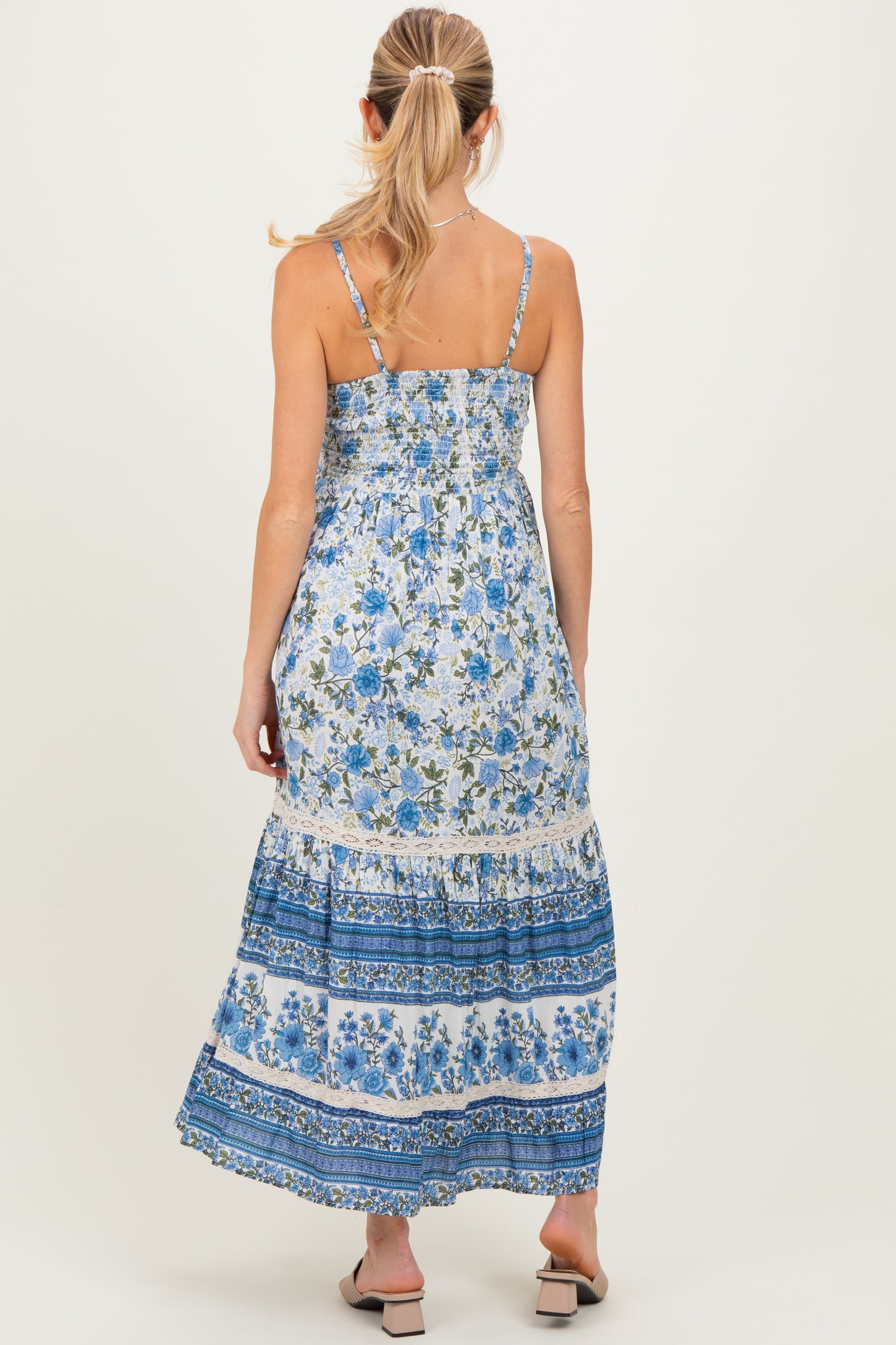 woman wearing a floral maternity maxi dress with blue and white patterns, showing a relaxed fit and adjustable straps