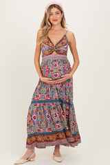 woman wearing a colorful floral print maternity maxi dress and holding her baby bump