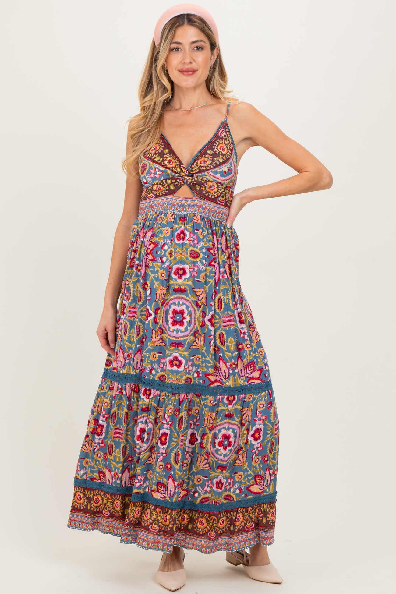 woman wearing a colorful patterned maternity maxi dress with a fitted bodice and flowy skirt, showing her baby bump