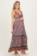woman wearing a floral print maternity maxi dress with a v-neckline and tiered skirt, showcasing her baby bump