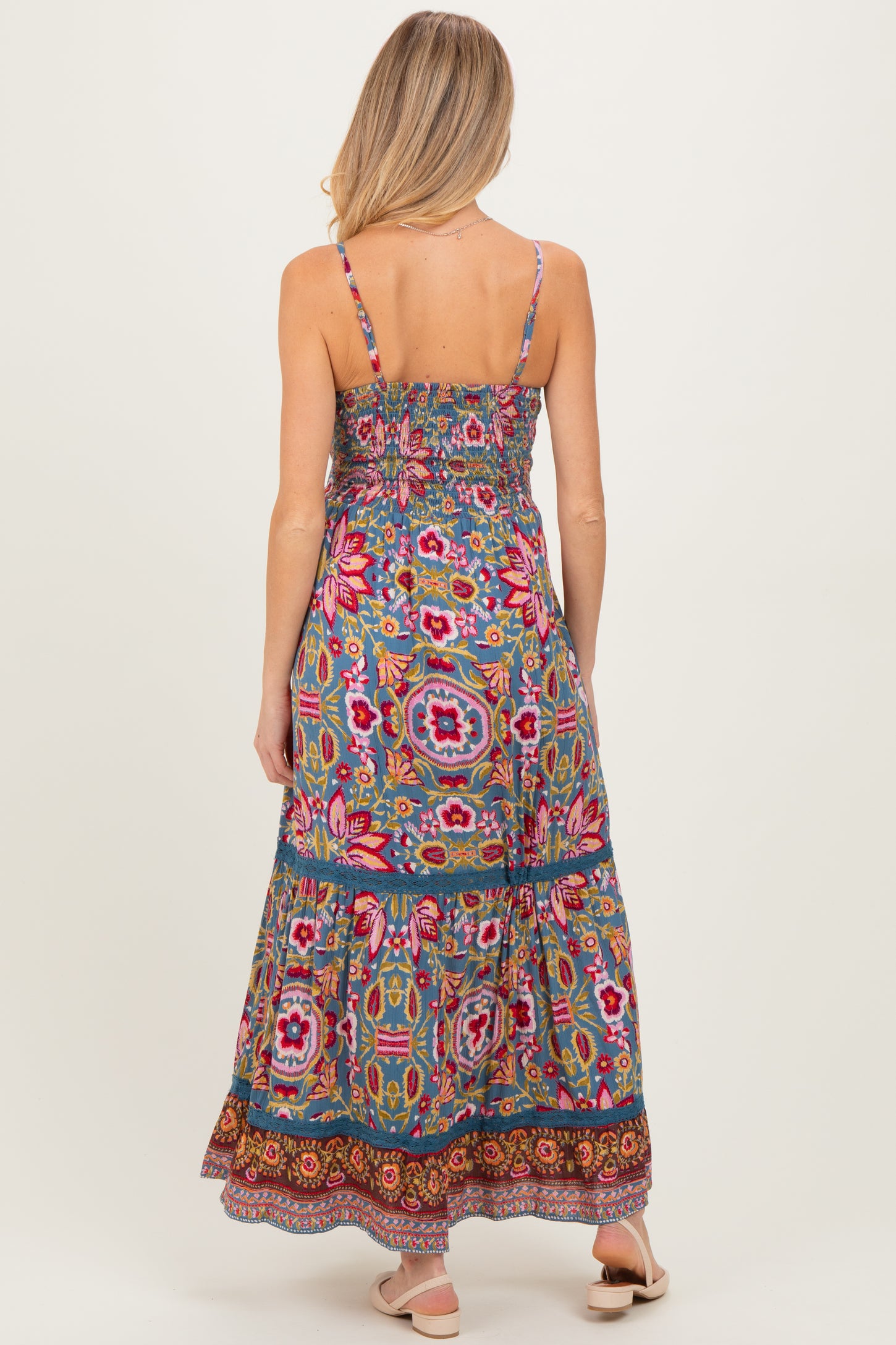 woman wearing a multi-colored floral maternity maxi dress with adjustable spaghetti straps and a smocked bodice