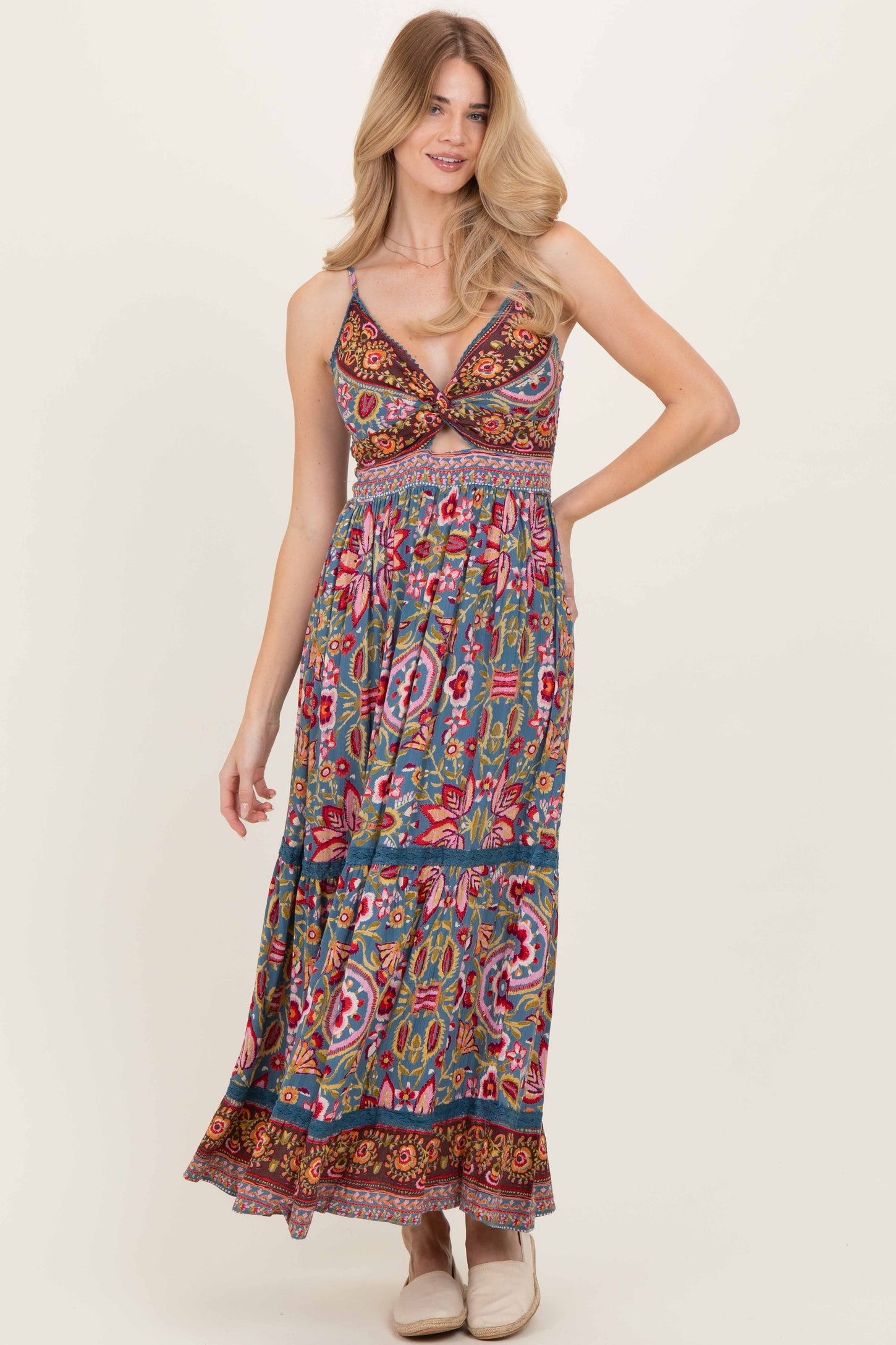 woman wearing a patterned maxi dress in teal with floral designs and a fitted bodice
