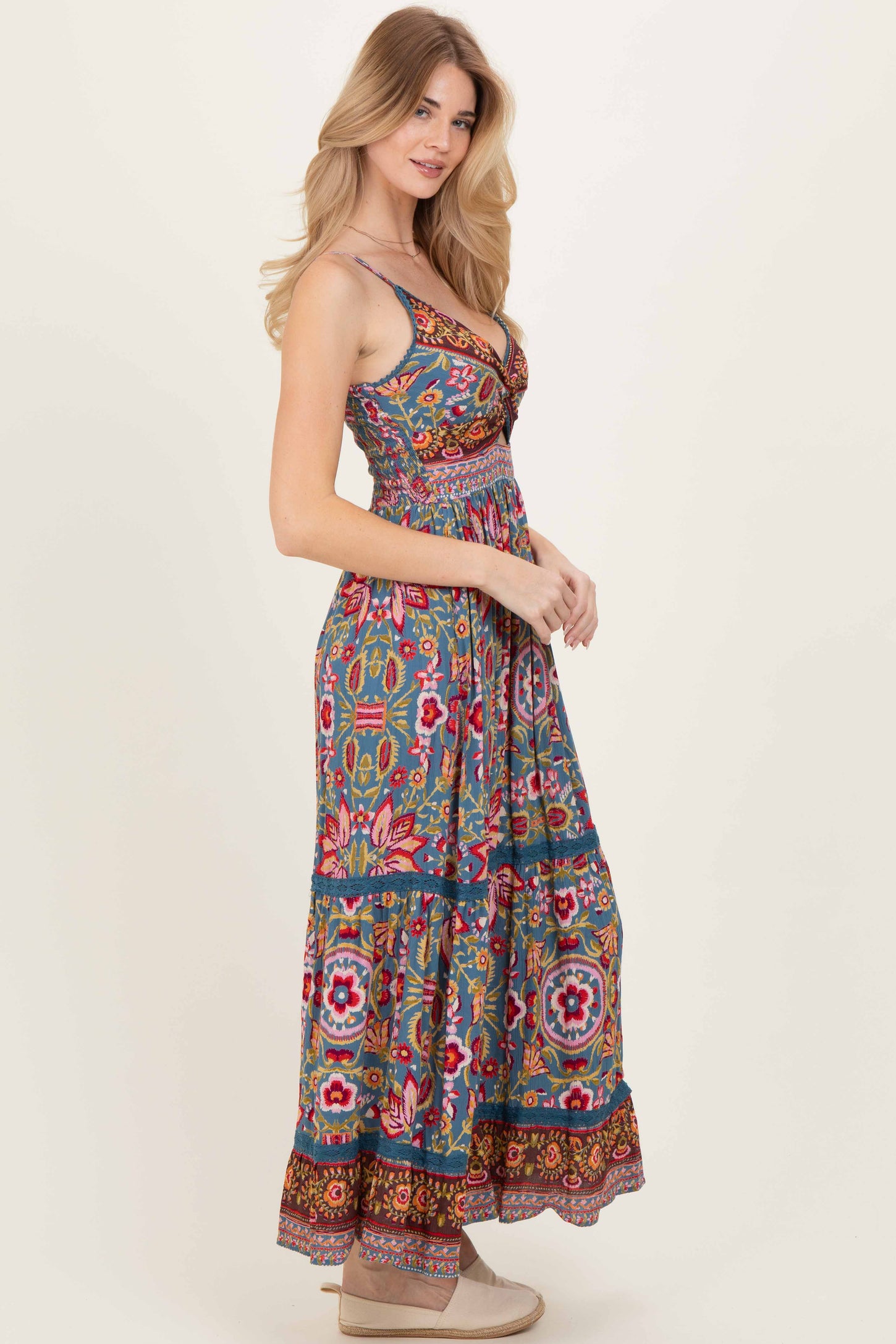 woman wearing a colorful bohemian maxi dress with floral patterns and a fitted bodice, posing sideways
