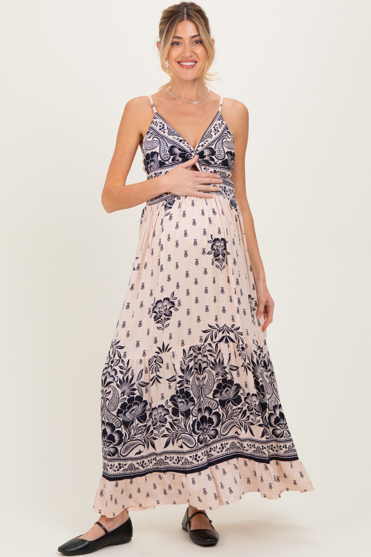 woman wearing a pink floral maternity maxi dress and holding her baby bump