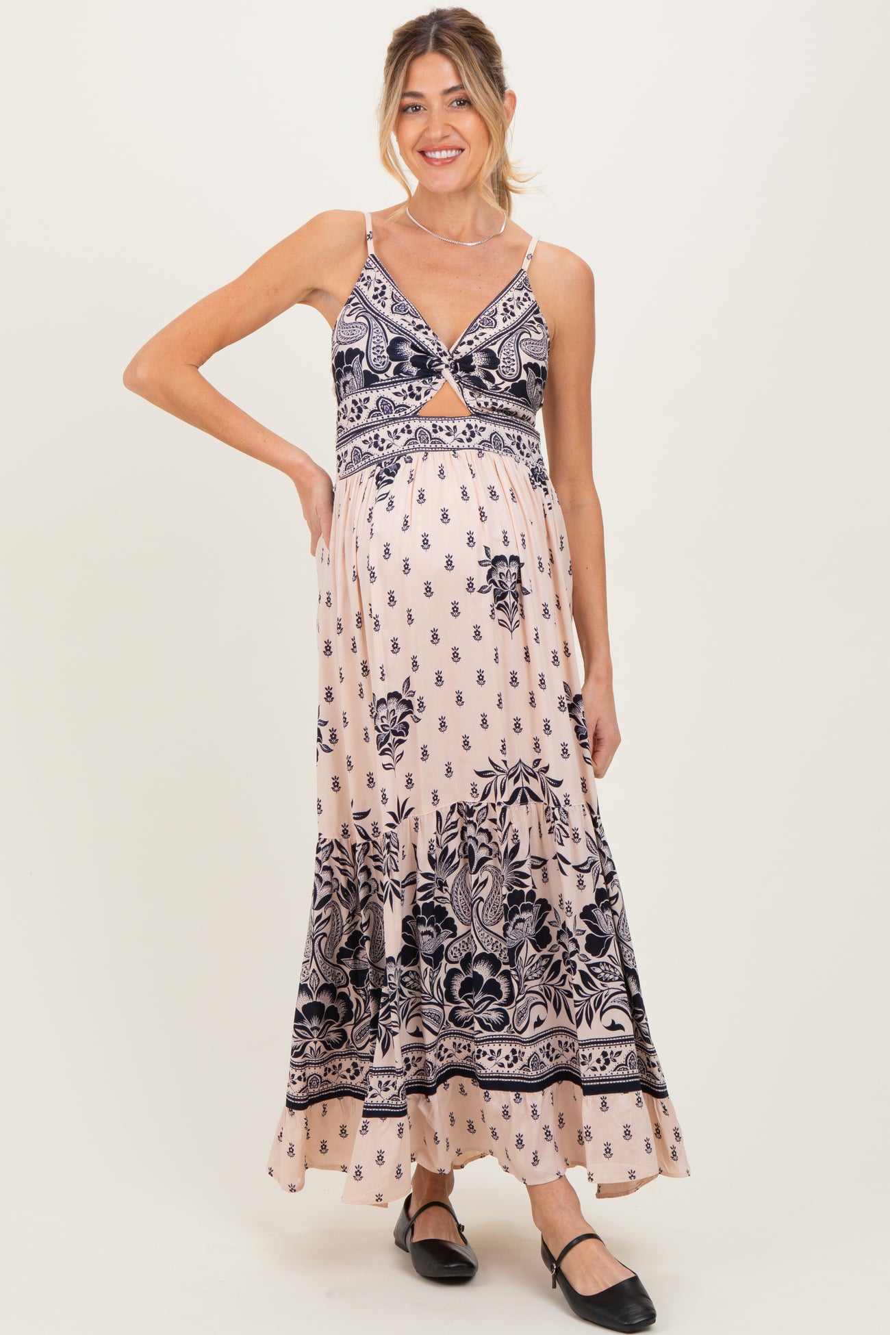 woman wearing a pink and navy floral maternity maxi dress with spaghetti straps and a baby bump visible