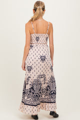 woman wearing a light pink maternity maxi dress with navy floral print, showing a smocked back design