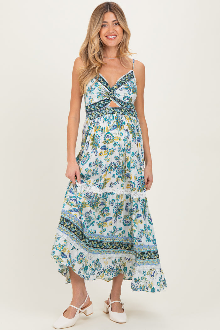 woman wearing a blue floral maternity maxi dress with a twist front and tiered skirt, showing her baby bump