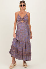woman wearing a printed purple maternity maxi dress with a knot detail and a fitted bodice, displaying her baby bump