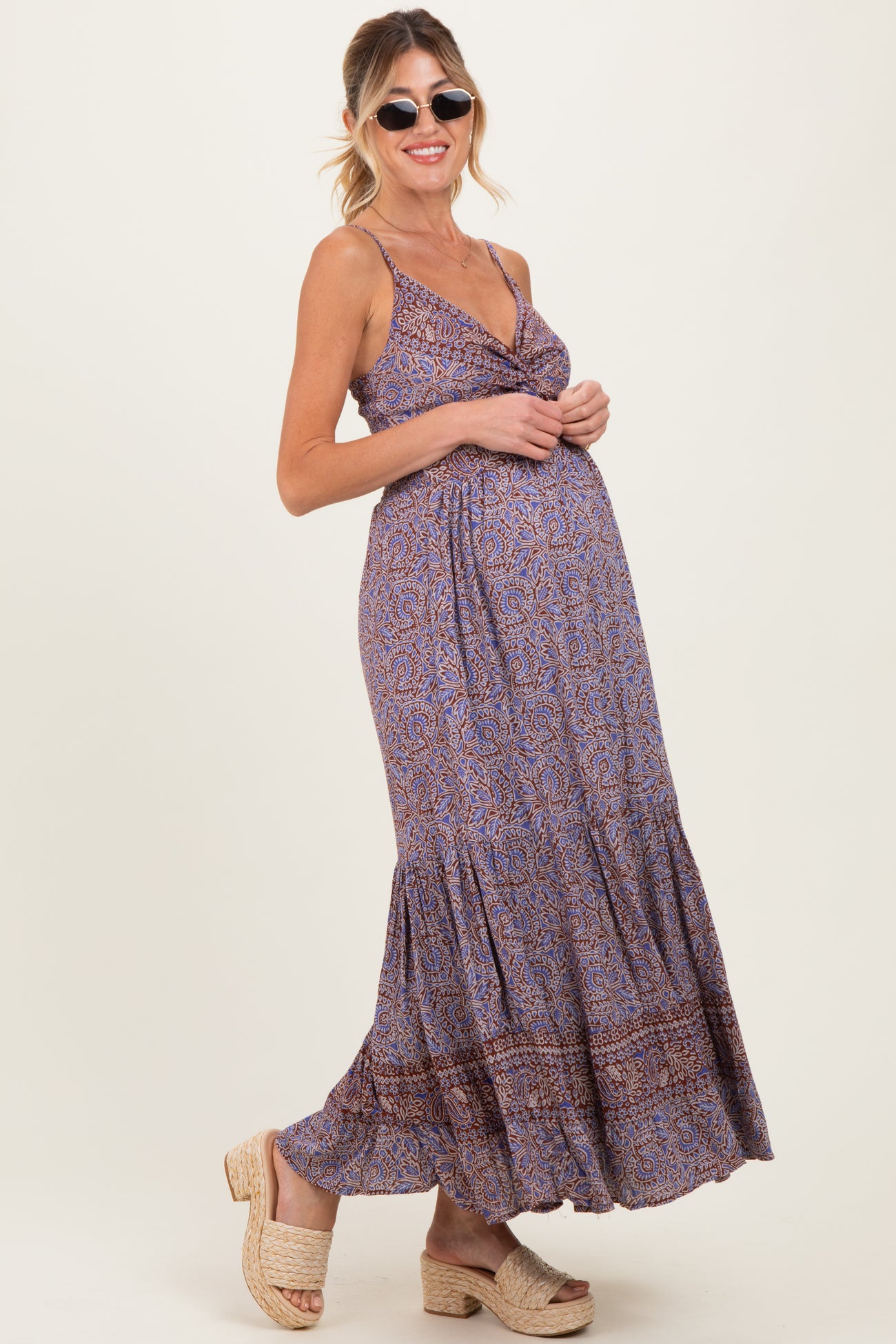 woman wearing a purple patterned maternity maxi dress with spaghetti straps and a visible baby bump