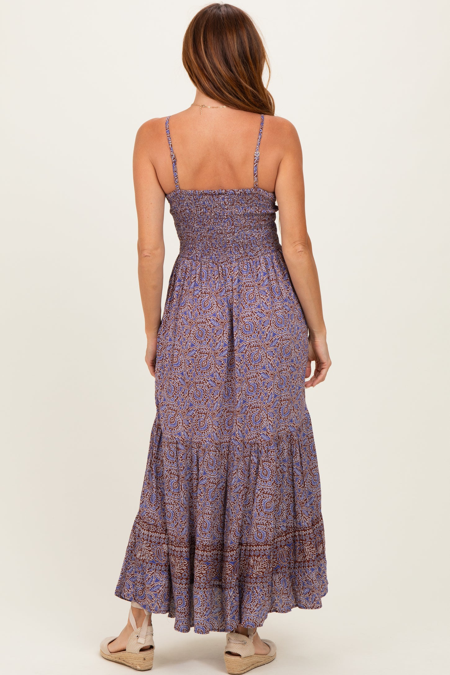 woman wearing a purple patterned maxi dress with smocked bodice and tiered skirt, viewed from the back