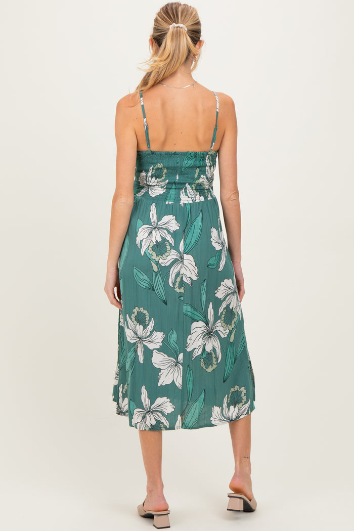 woman wearing a green floral maternity dress with a smocked bodice and flowy skirt, showing off her baby bump from the back