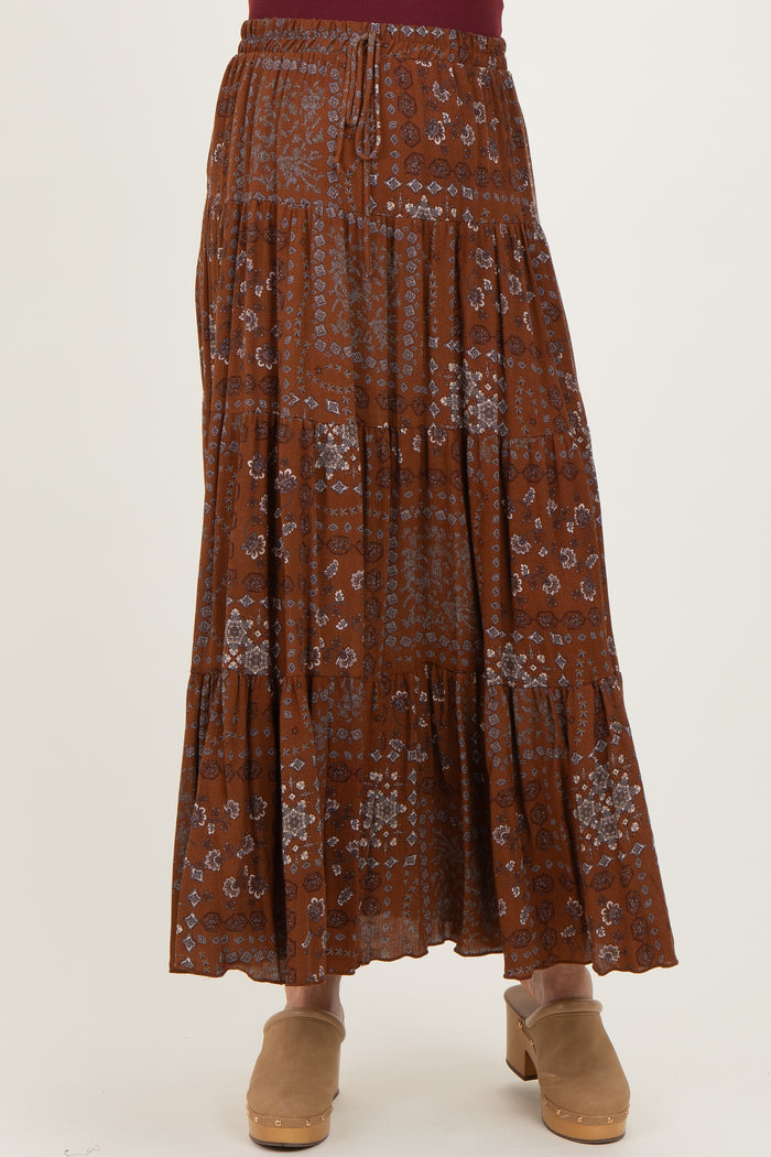 maternity wear woman wearing a rust-colored tiered maxi skirt with floral patterns and an elastic waistband