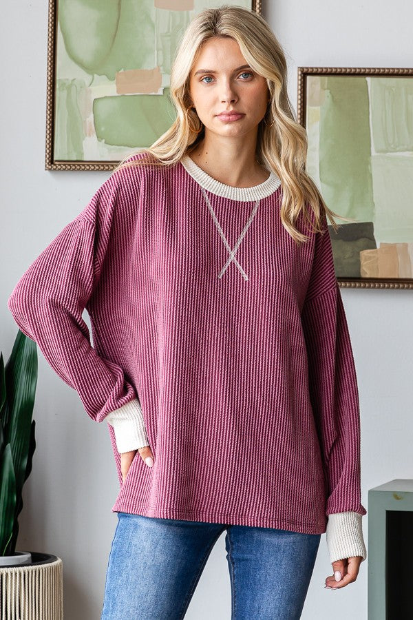 woman wearing a raspberry-colored long sleeve waffle knit pullover with cream cuffs and a relaxed fit