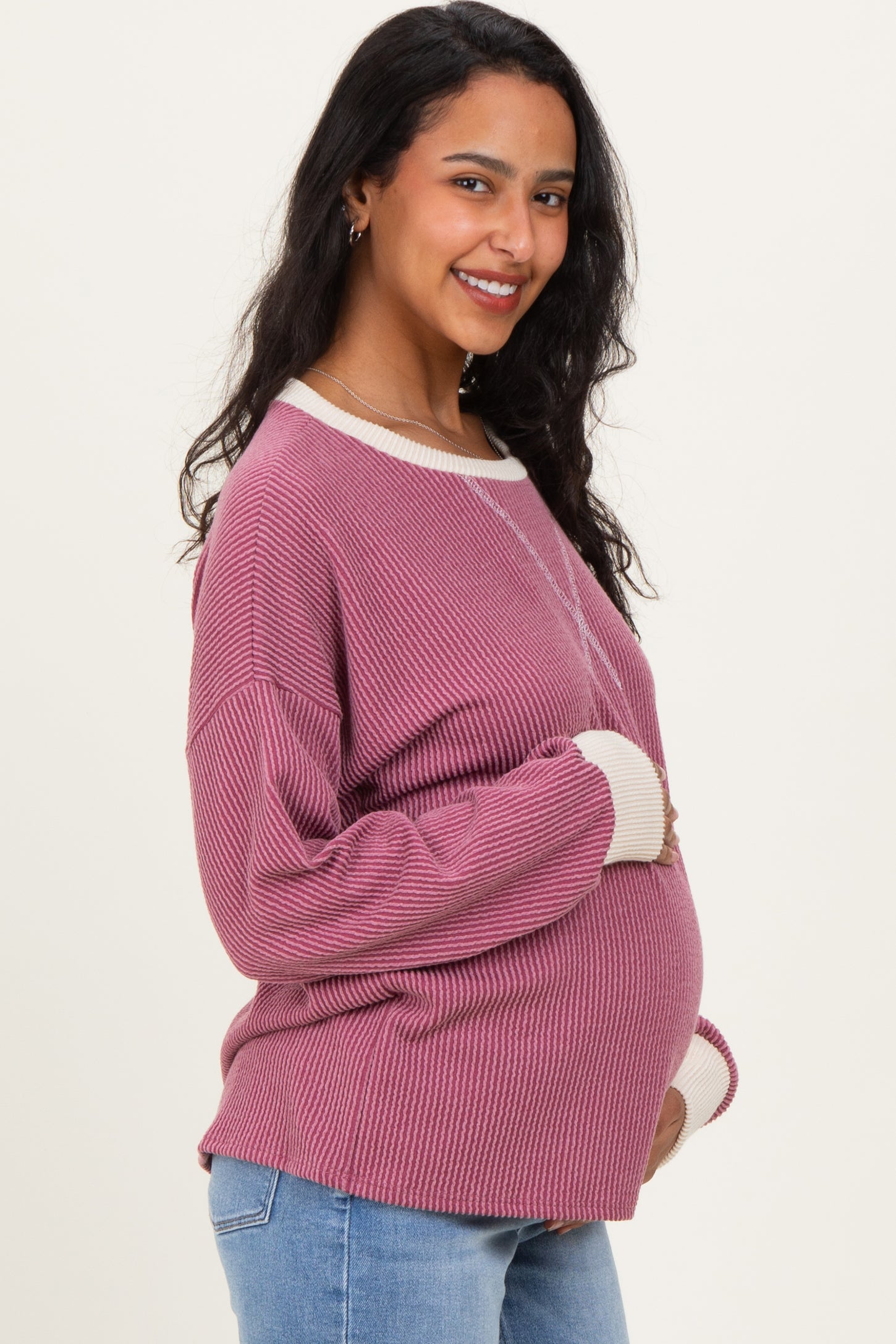 woman wearing a maroon striped maternity sweater with cream detailing and a visible baby bump