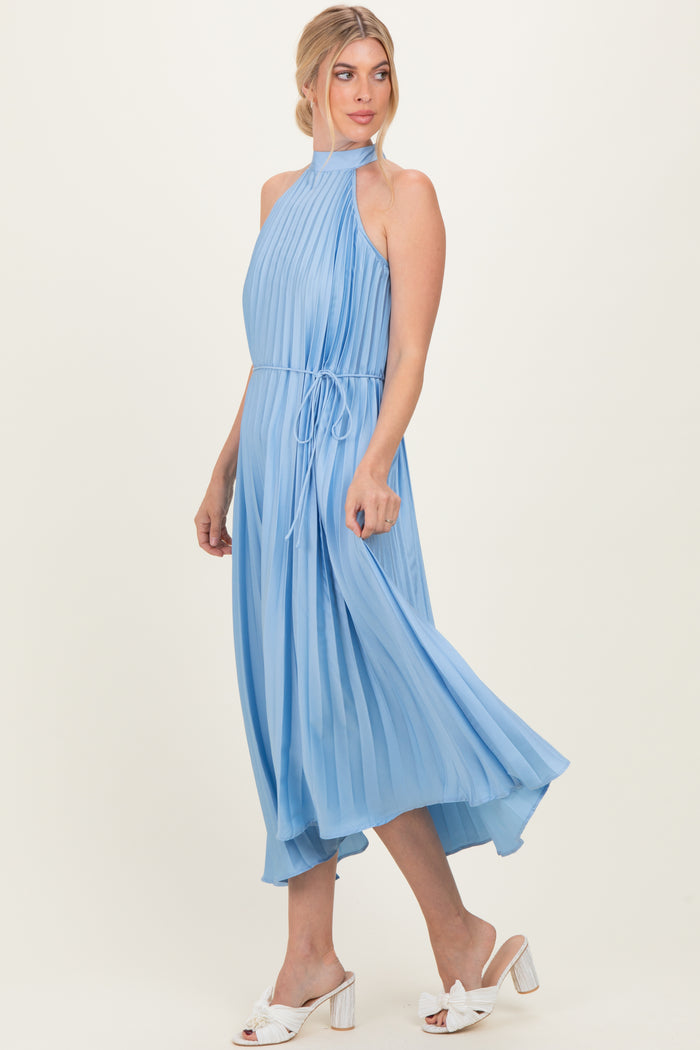 woman wearing a light blue pleated halter dress with a tie waist and flowing skirt