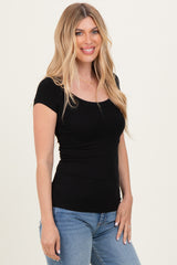 woman wearing a black ribbed short sleeve top with a scoop neck and styled with light blue jeans