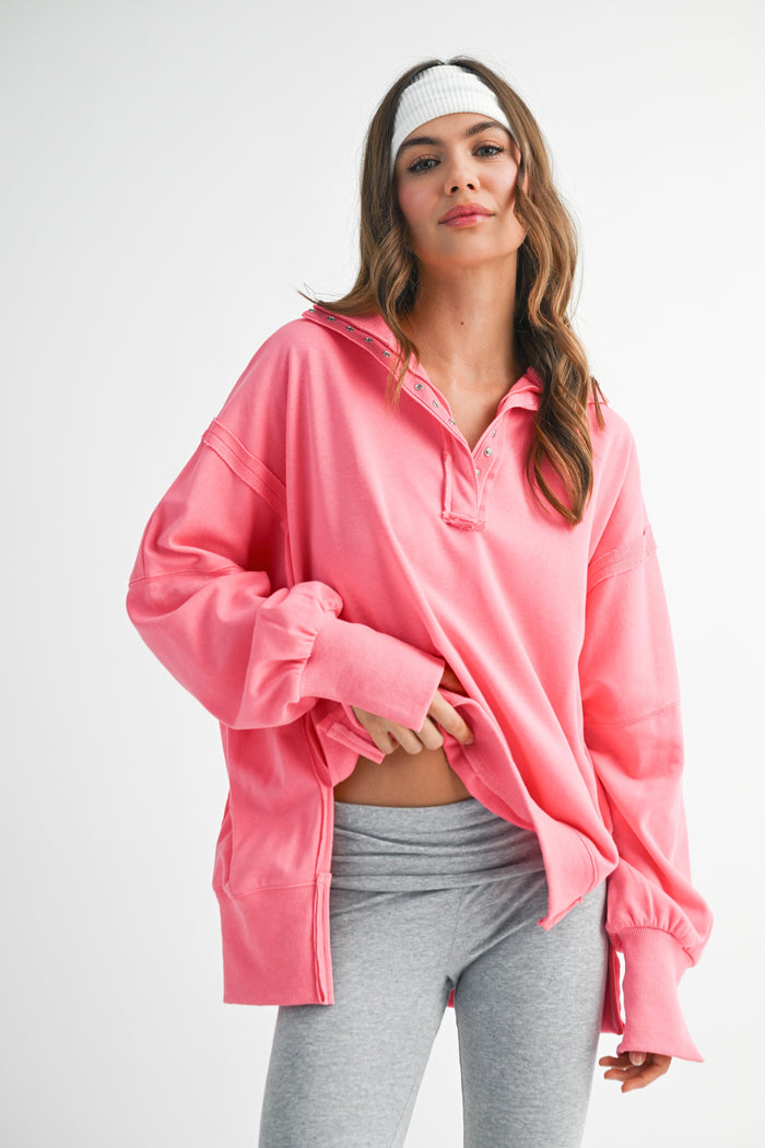 woman wearing a bright pink oversized pullover with a collar and long sleeves, paired with gray leggings