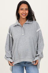 woman wearing a gray maternity pullover with a collar and long sleeves, showing her baby bump