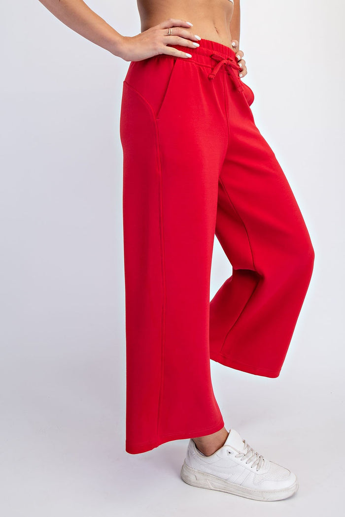 woman wearing bright red wide-leg sweatpants with pockets and a drawstring waist, styled with white sneakers
