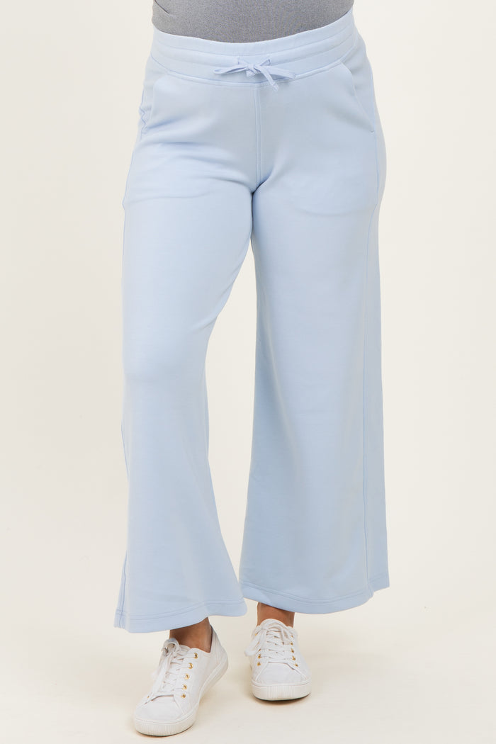 woman wearing light blue maternity wide-leg sweatpants with a drawstring waistband and white sneakers