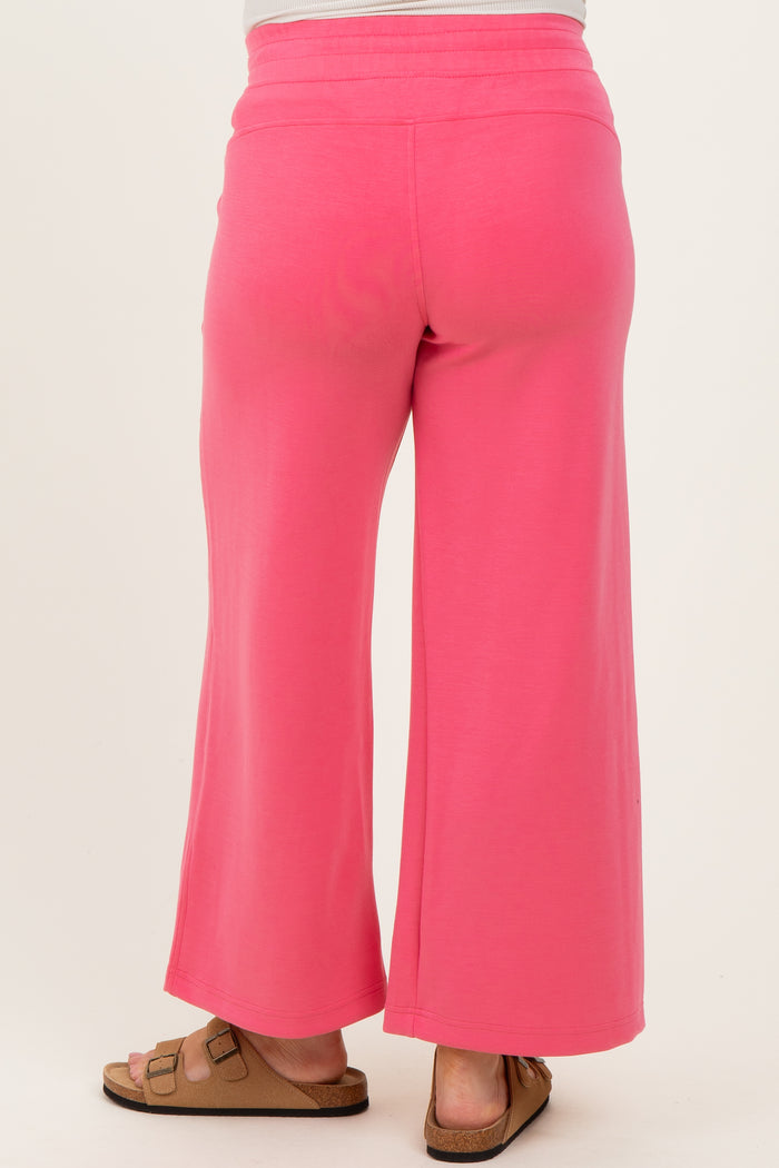woman wearing bright pink maternity wide-leg pants, showing the back view with a relaxed fit