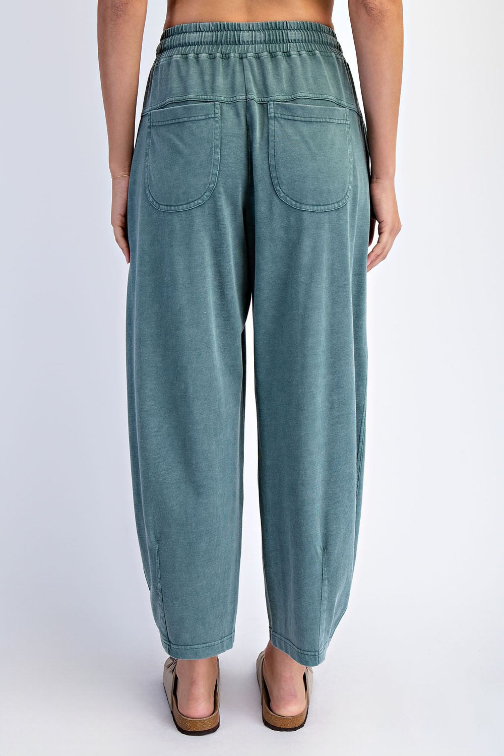 woman wearing light green relaxed fit pants with elastic waistband and two back pockets, seen from the back