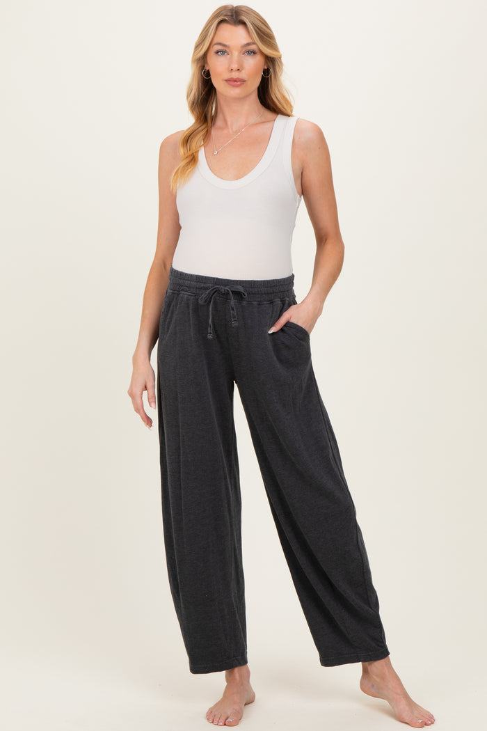 woman wearing a white ribbed tank top and dark gray maternity lounge pants with pockets and a drawstring waistband