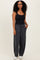 woman wearing a black tank top and dark gray wide-leg sweatpants with pockets, standing in a casual pose