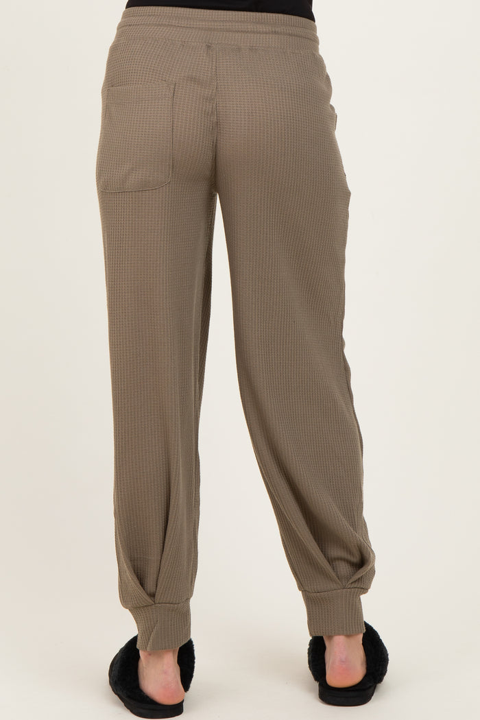 woman wearing khaki ribbed maternity jogger pants, showing the back view with side pockets and elastic cuffs