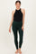 woman wearing a black halter top and dark green maternity leggings, showing a baby bump