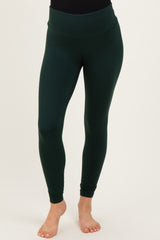 woman wearing dark green maternity leggings with a high waistband