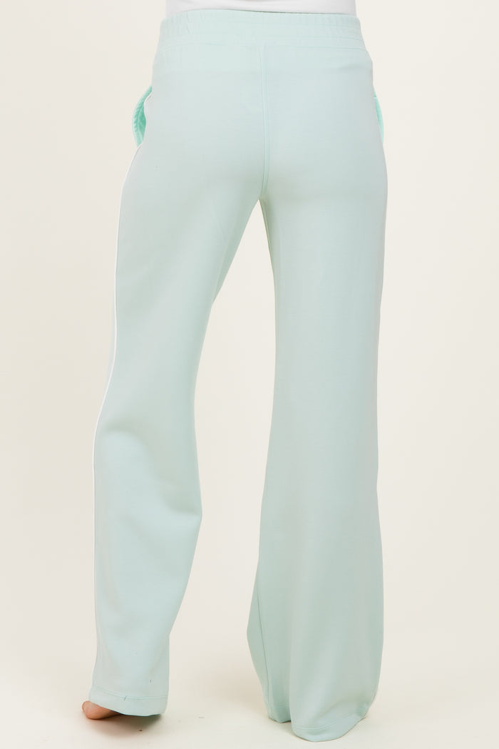 maternity wear in mint green, featuring wide-leg pants with a relaxed fit and side pockets, worn by a model from the back