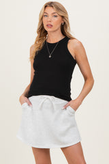 woman wearing a black ribbed tank top and a light gray drawstring maternity skort with pockets