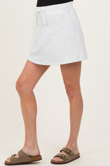 woman wearing a light gray maternity skort with drawstring waist and side pockets, paired with brown slide sandals