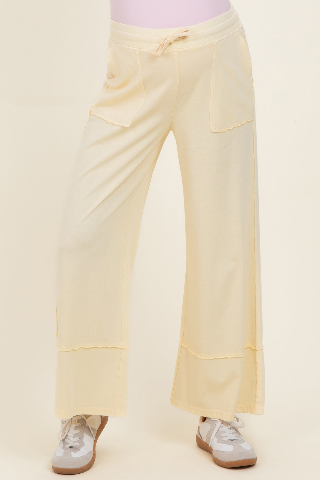 maternity wear in a soft yellow color featuring wide leg design and front pockets, styled with sneakers